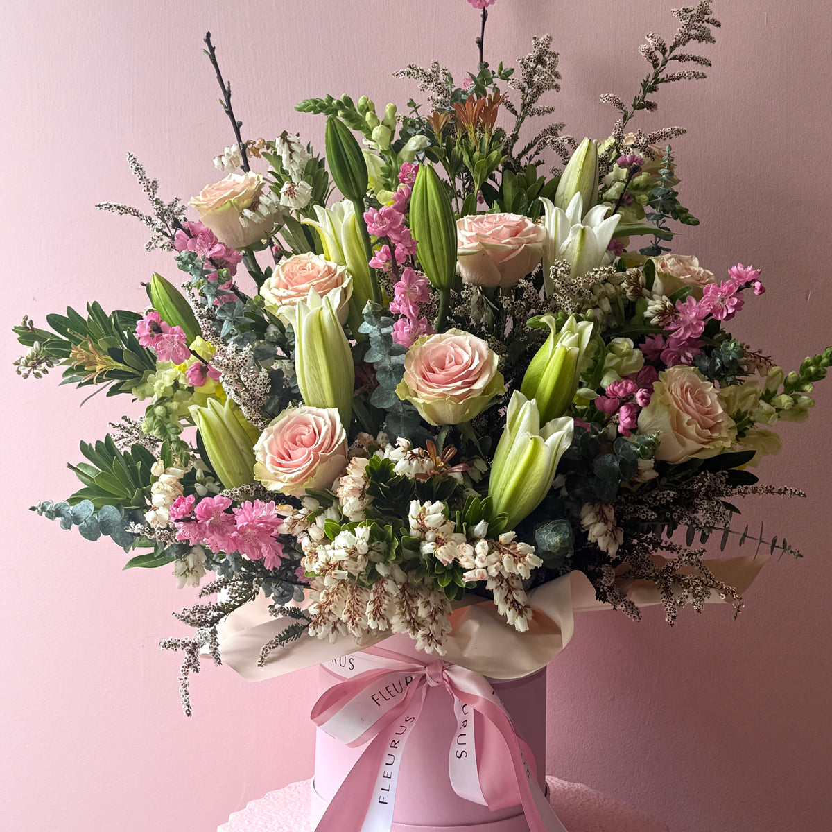 Pastel seasonal flowers arranged in a white Fleurus hat box.