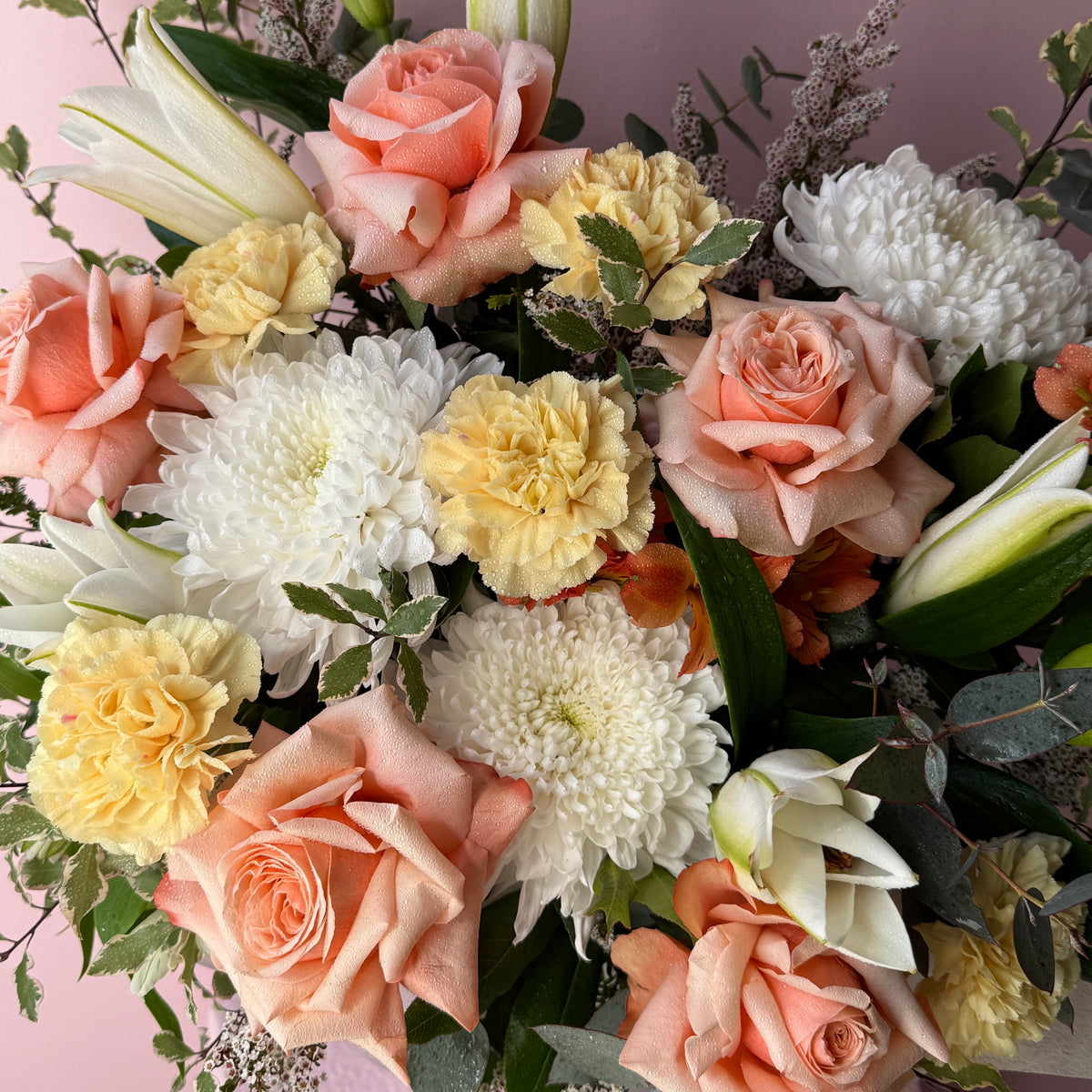 Close-up of the apricot and peach seasonal flowers in the hat box arrangement.