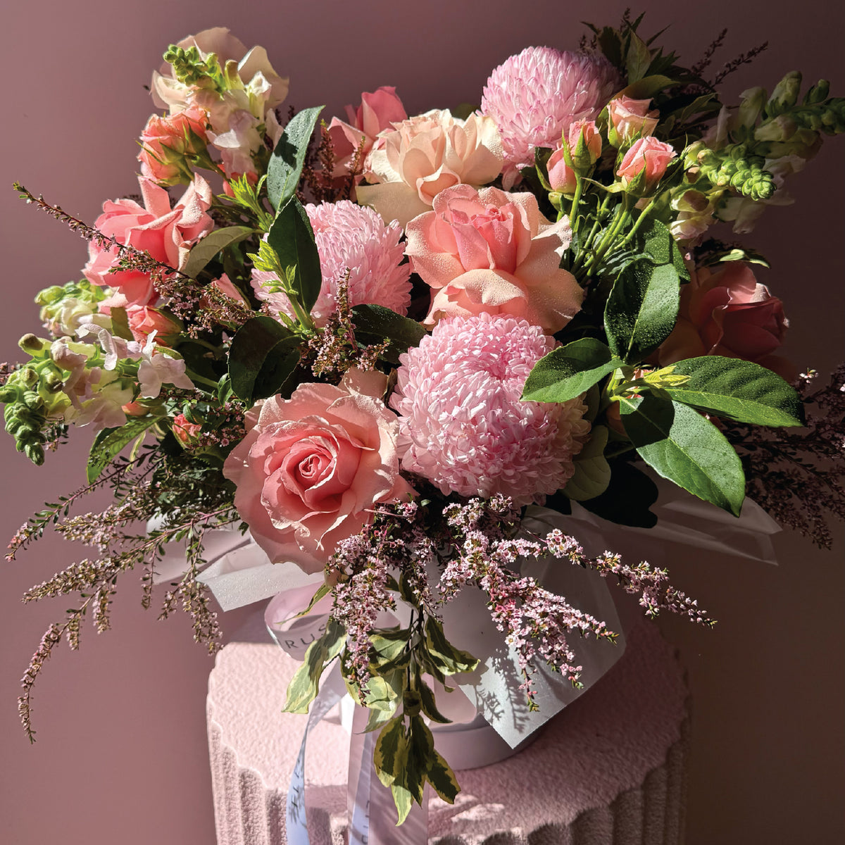 Pink seasonal flower arrangement presented in a white Fleurus hat box.