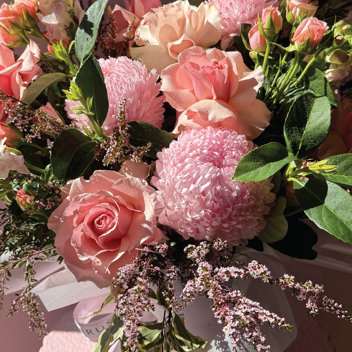 Close-up of the pink seasonal flowers in the white Fleurus hat box arrangement.